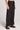 Side angle view of a woman wearing the Saltwater Luxe Woven Black Pull On Pant on a neutral background