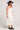 Side angle view of a woman wearing the Saltwater Luxe Woven Ecru Tank Midi Dress on a neutral background