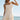 Front view of a woman wearing the Saltwater Luxe Zevya Salt Mini Dress and a hat in front of the ocean