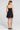 Back view of a woman wearing the Saltwater Luxe Zurina Black Mini Dress on a neutral background