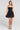 Front view of a woman wearing the Saltwater Luxe Zurina Black Mini Dress on a neutral background