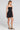 Side angle view of a woman wearing the Saltwater Luxe Zurina Black Mini Dress on a neutral background